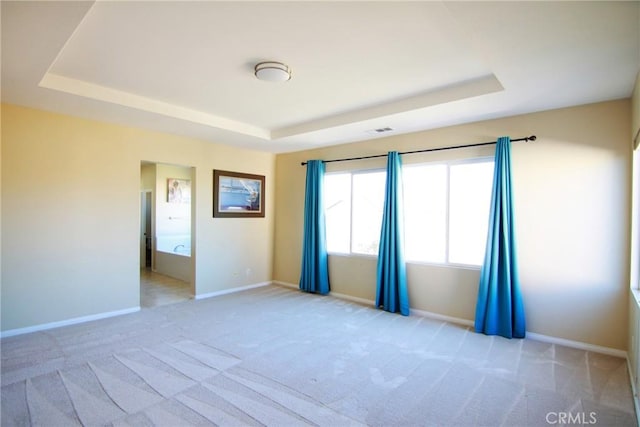 carpeted empty room with a raised ceiling