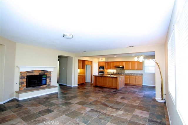 kitchen featuring stainless steel microwave, sink, a fireplace, and a center island