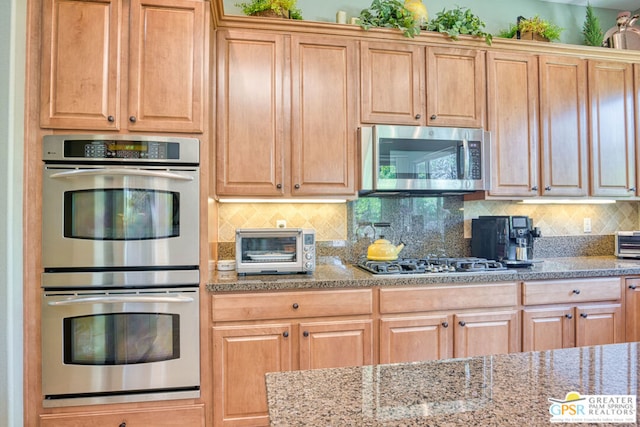 kitchen featuring light stone counters, tasteful backsplash, and appliances with stainless steel finishes