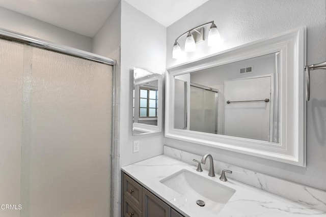 bathroom with walk in shower and vanity