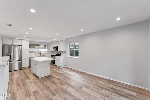 kitchen featuring stainless steel appliances, a center island, sink, and white cabinets