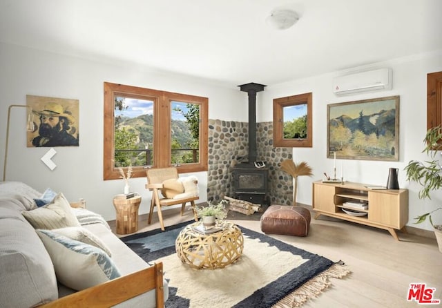 living room featuring a wood stove, a wall unit AC, and light hardwood / wood-style floors