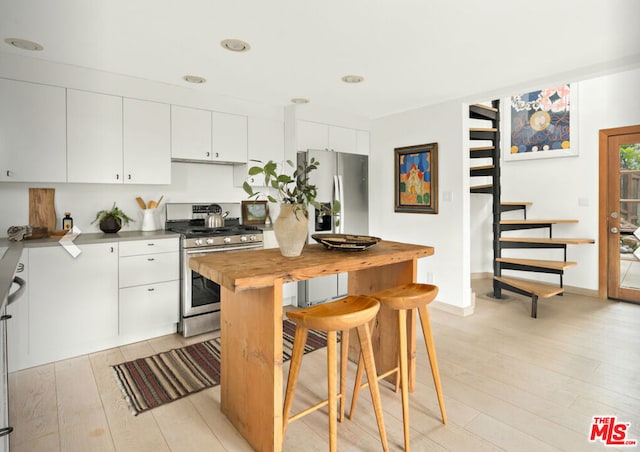 kitchen with wood counters, stainless steel appliances, light hardwood / wood-style flooring, and white cabinets