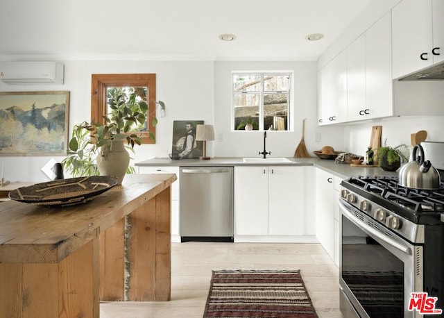 kitchen featuring white cabinetry, appliances with stainless steel finishes, sink, and an AC wall unit