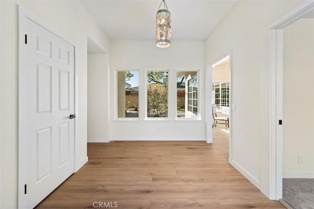 corridor featuring a chandelier and light hardwood / wood-style flooring