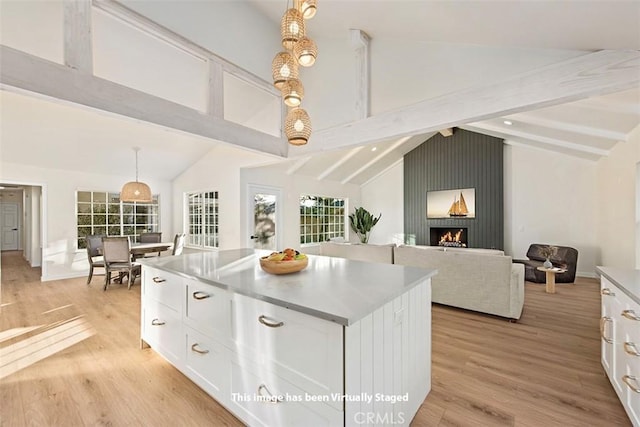 kitchen with lofted ceiling with beams, white cabinetry, a center island, and pendant lighting