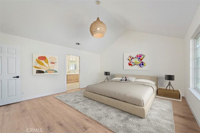 bedroom featuring ensuite bath, wood-type flooring, and vaulted ceiling