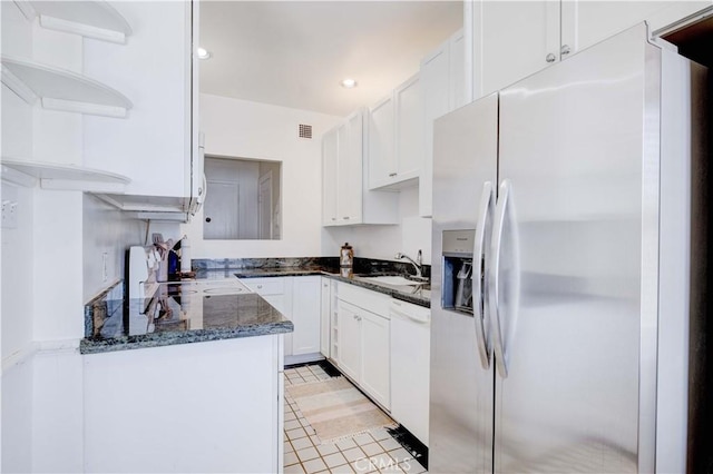 kitchen with sink, dishwasher, stainless steel refrigerator with ice dispenser, white cabinets, and dark stone counters