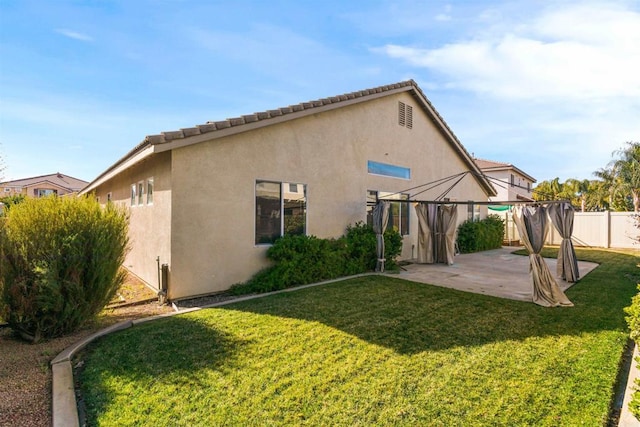 back of property with a gazebo, a patio, and a lawn