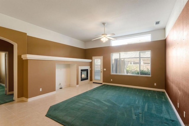 unfurnished living room featuring a tiled fireplace, tile patterned floors, and ceiling fan