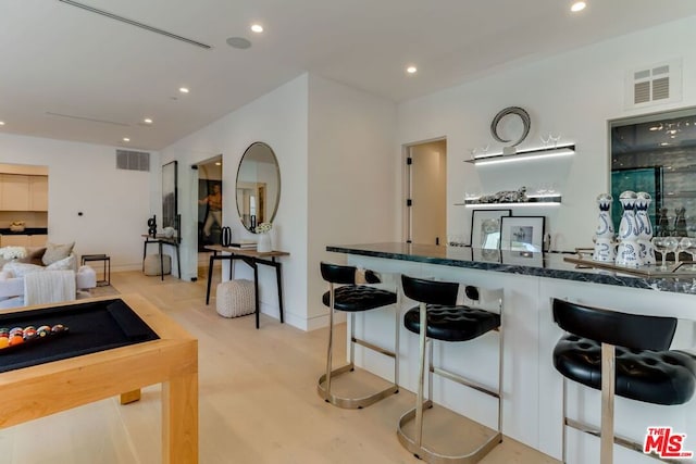 kitchen featuring dark stone countertops, a breakfast bar area, and light hardwood / wood-style floors