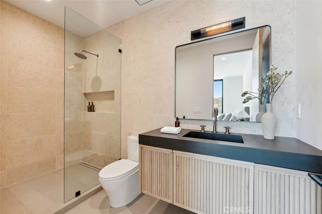 bathroom with vanity, tile walls, toilet, and tiled shower