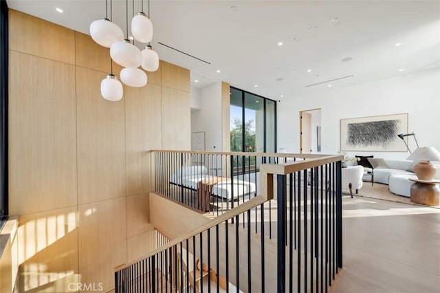 stairs with an inviting chandelier, expansive windows, and wood walls