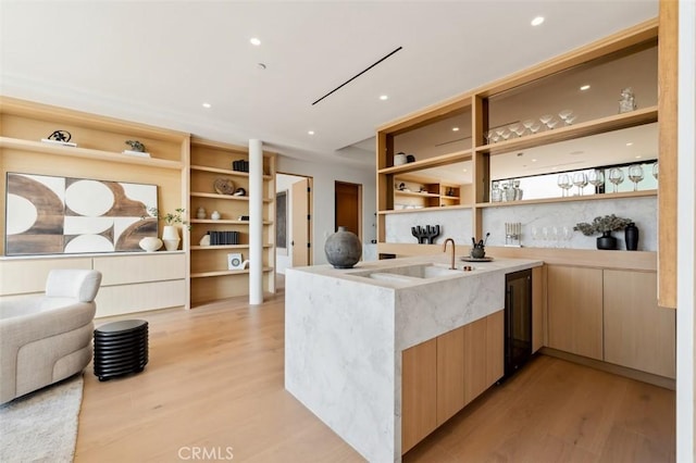 bar featuring light brown cabinetry, sink, and light wood-type flooring