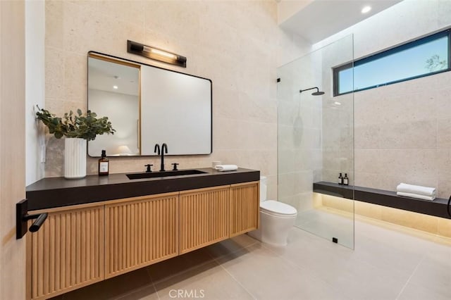 bathroom featuring tile patterned flooring, tile walls, tiled shower, vanity, and toilet