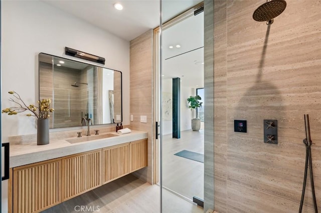 bathroom with tiled shower and vanity