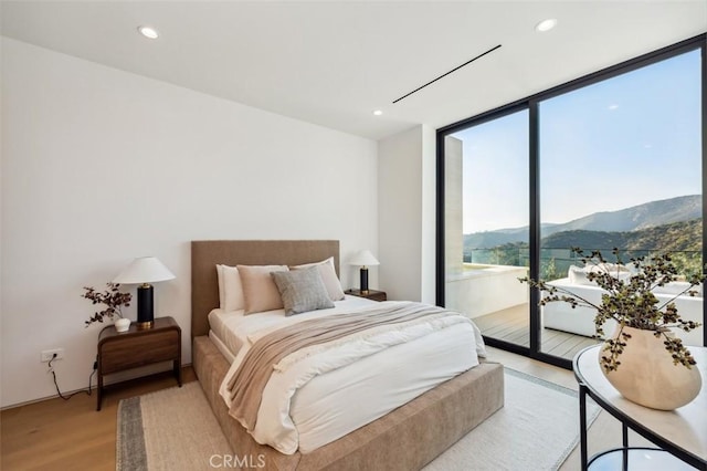 bedroom featuring expansive windows, a mountain view, access to exterior, and light wood-type flooring