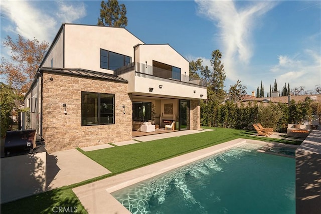 back of property featuring a patio, a balcony, a lawn, an outdoor hangout area, and a fenced in pool