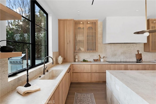 kitchen with light brown cabinetry, sink, light stone counters, dark wood-type flooring, and black electric cooktop