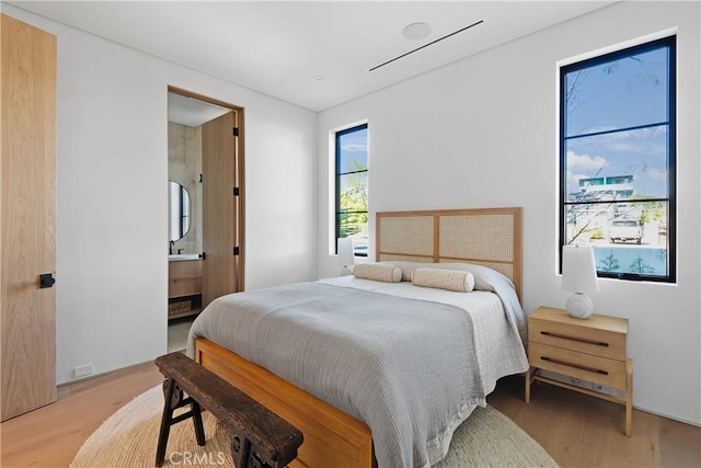 bedroom featuring connected bathroom and hardwood / wood-style flooring