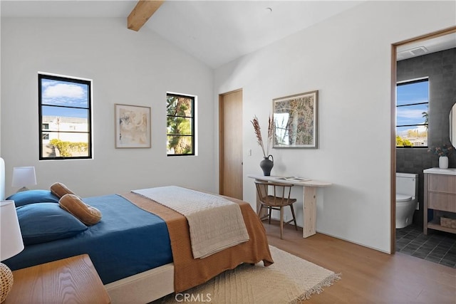 bedroom featuring ensuite bath, lofted ceiling with beams, and light hardwood / wood-style flooring