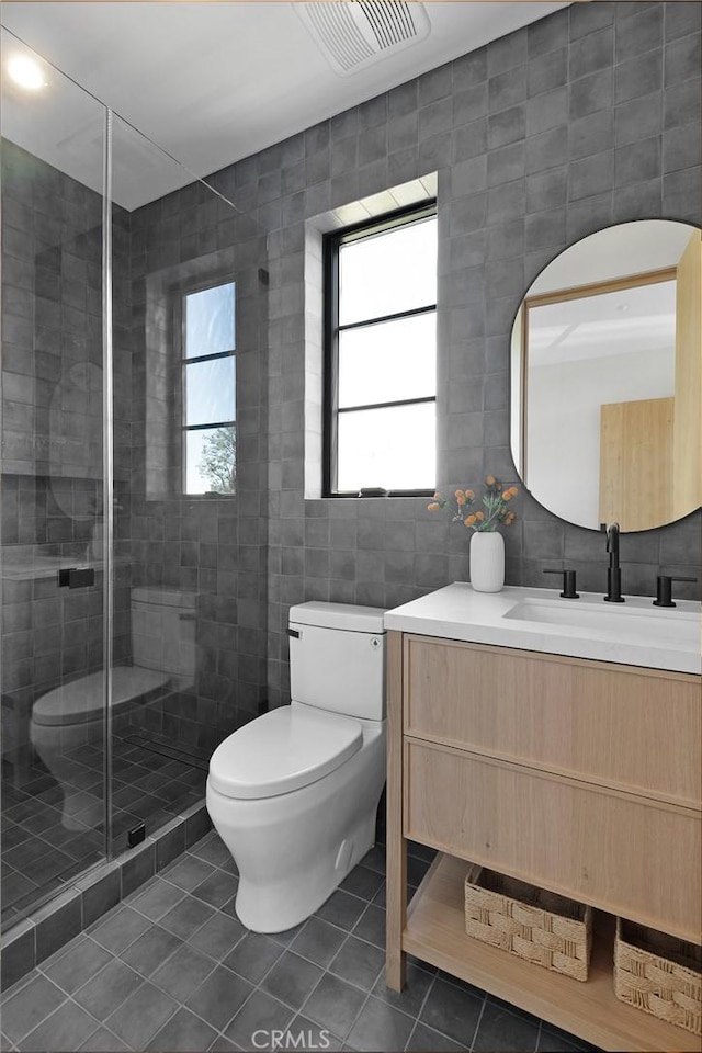 bathroom featuring tile walls, vanity, an enclosed shower, toilet, and tile patterned floors