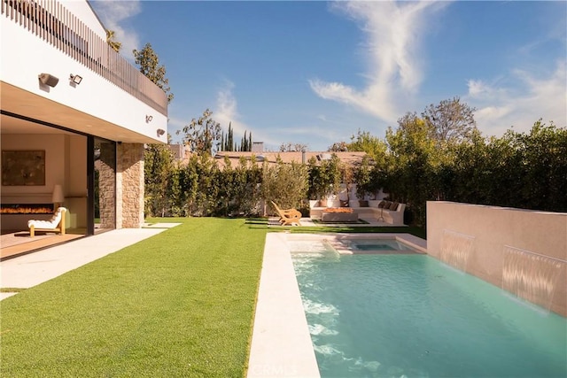 view of pool with a yard, an outdoor living space with a fireplace, and a patio area