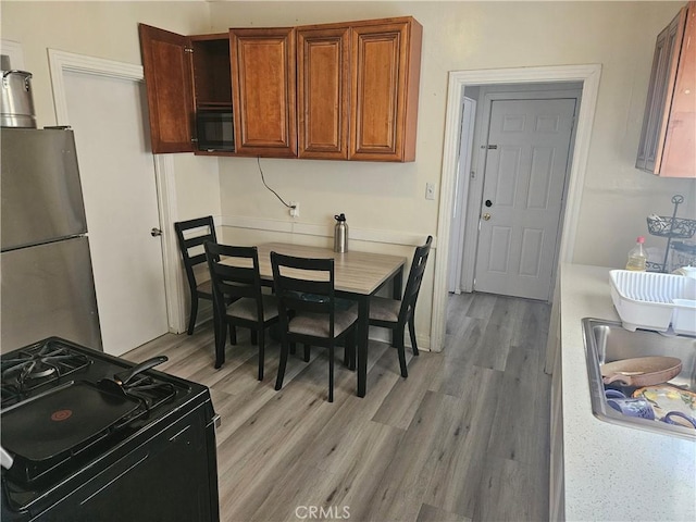 kitchen featuring sink, black appliances, and light wood-type flooring