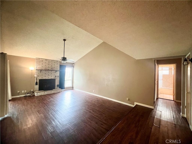 unfurnished living room featuring a brick fireplace, vaulted ceiling, dark hardwood / wood-style floors, and ceiling fan