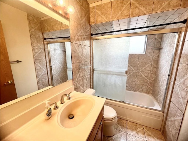 full bathroom featuring toilet, tile patterned floors, vanity, and bath / shower combo with glass door