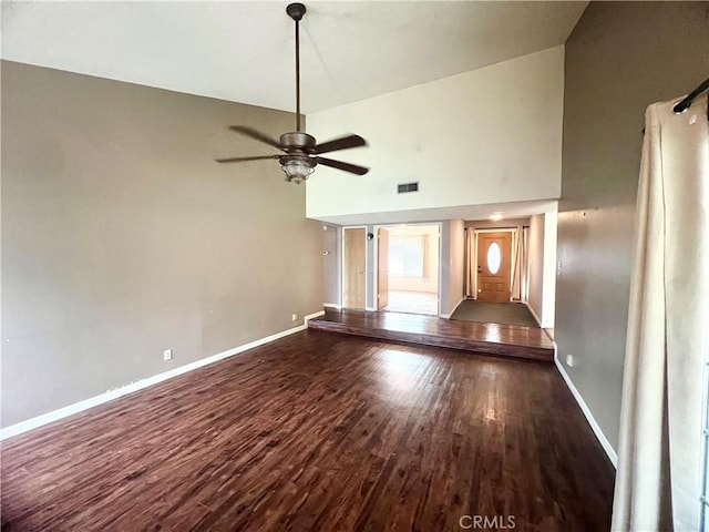 unfurnished living room featuring high vaulted ceiling, dark wood-type flooring, and ceiling fan