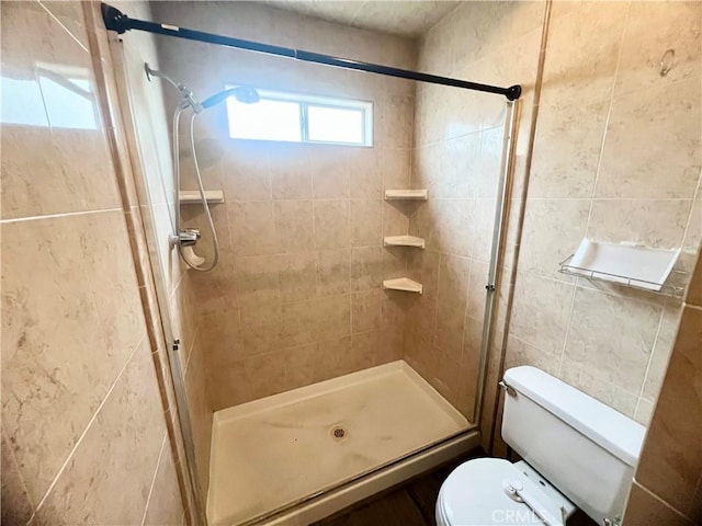 bathroom featuring a shower with door, tile walls, and toilet