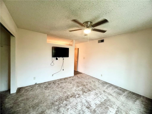 unfurnished bedroom with ceiling fan, carpet, a textured ceiling, and a closet