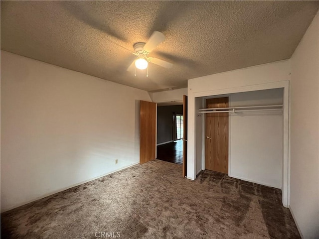 unfurnished bedroom with dark colored carpet, ceiling fan, a textured ceiling, and a closet