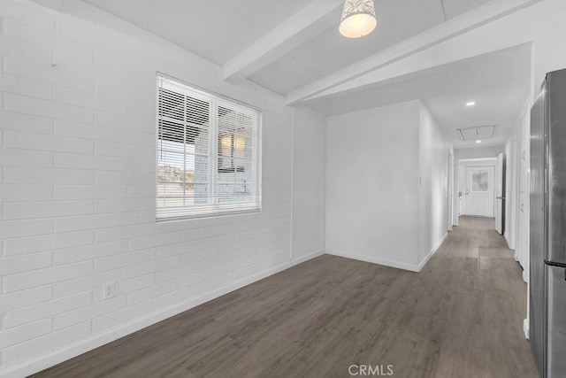 unfurnished room with beamed ceiling, brick wall, and dark hardwood / wood-style floors