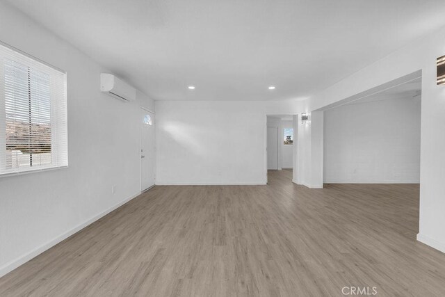 empty room with a wall mounted air conditioner and light wood-type flooring