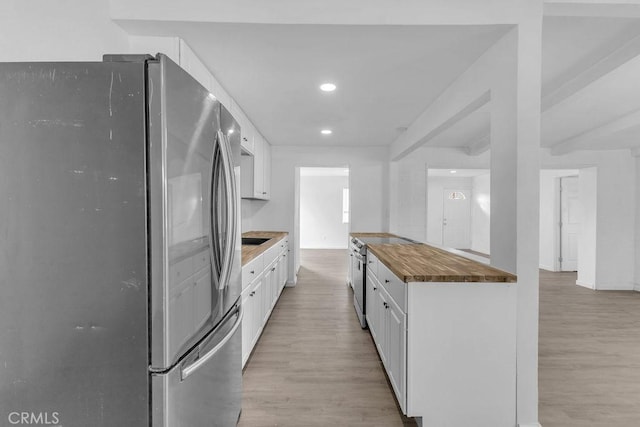 kitchen with white cabinetry, appliances with stainless steel finishes, butcher block countertops, and light hardwood / wood-style flooring