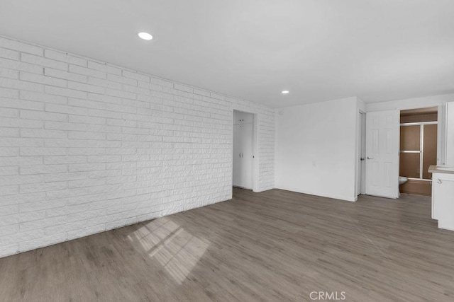 interior space with dark wood-type flooring and brick wall