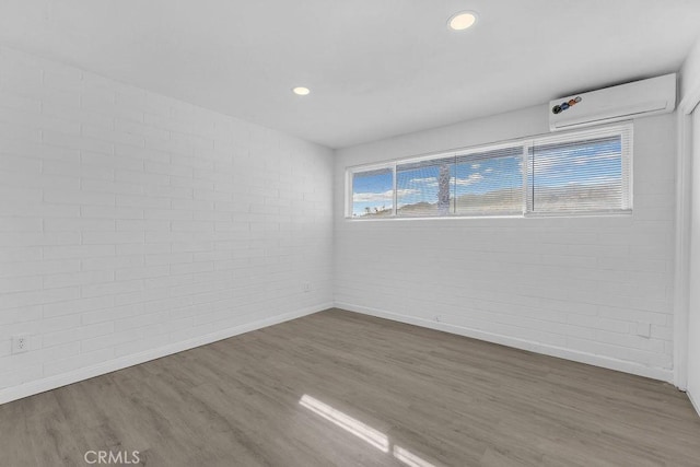 spare room with brick wall, dark wood-type flooring, and a wall mounted AC