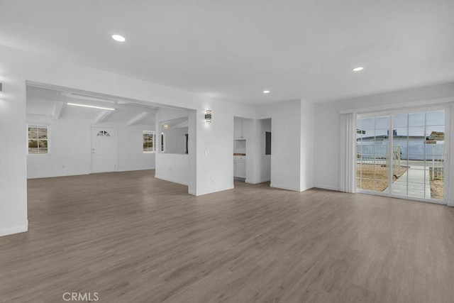 unfurnished living room with hardwood / wood-style floors and beam ceiling