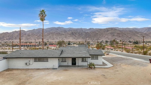 back of property with a mountain view and a patio area