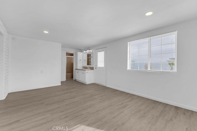 unfurnished living room featuring light hardwood / wood-style flooring and a notable chandelier