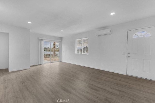 unfurnished living room with a wall mounted air conditioner and dark hardwood / wood-style floors