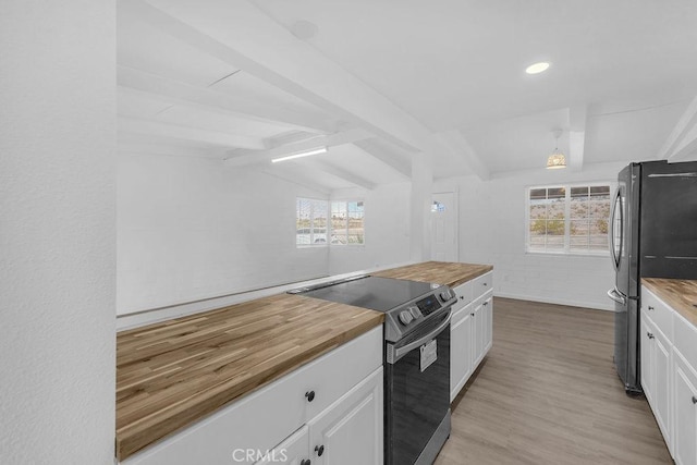 kitchen with wood counters, appliances with stainless steel finishes, vaulted ceiling with beams, white cabinetry, and light hardwood / wood-style floors