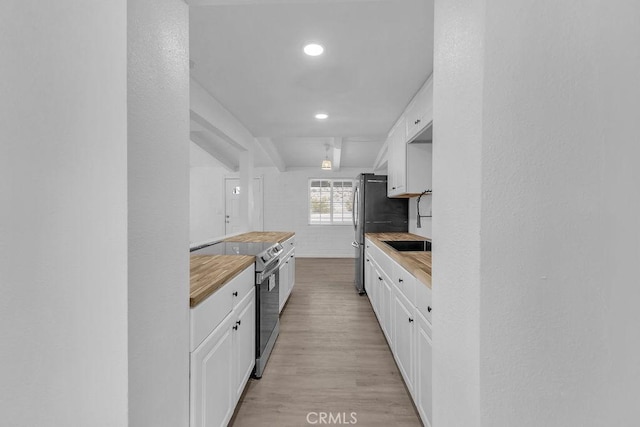 kitchen featuring appliances with stainless steel finishes, white cabinetry, butcher block counters, and light hardwood / wood-style flooring