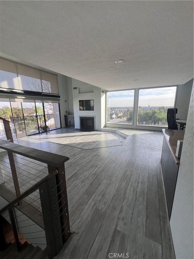 unfurnished living room with expansive windows, wood-type flooring, and a textured ceiling