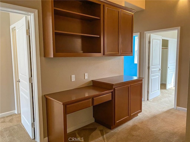 unfurnished office featuring built in desk and light carpet