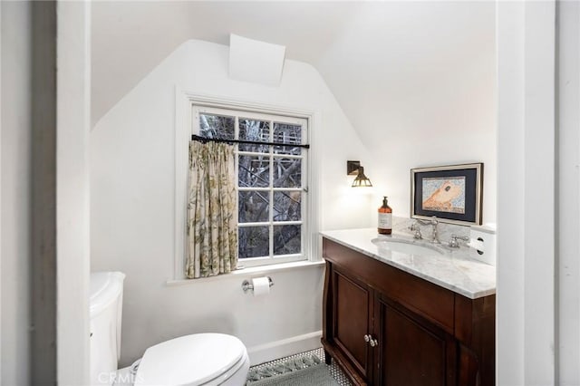 bathroom featuring vanity, toilet, and vaulted ceiling