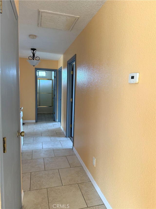 corridor featuring light tile patterned floors, baseboards, and visible vents