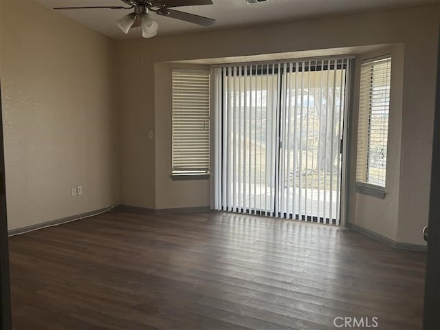 spare room with dark wood finished floors, baseboards, and ceiling fan